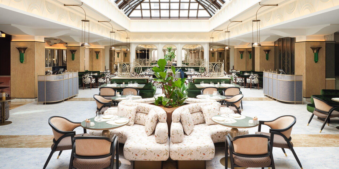 A modern white and light wood lobby with banquettes, a curved glass atrium, and subtle Secessionist design elements.