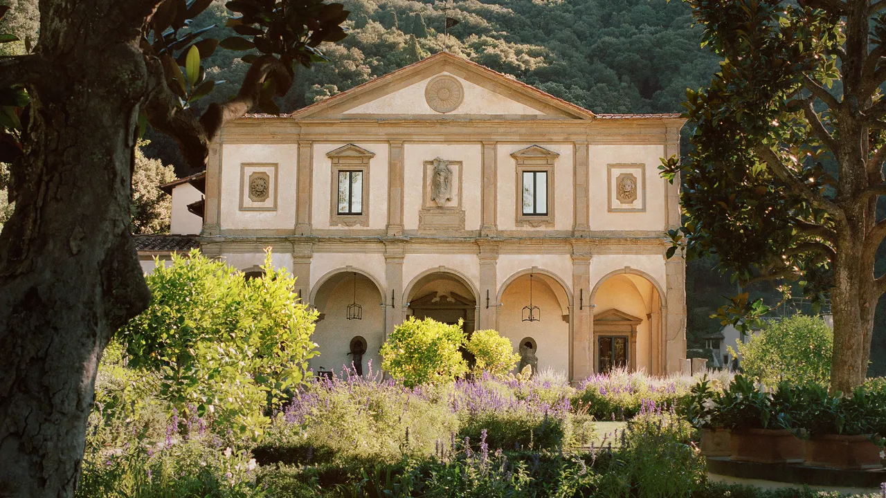 Exterior view of Villa San Michele, an elegant Renaissance building surrounded by lush trees and offering views of a valley
