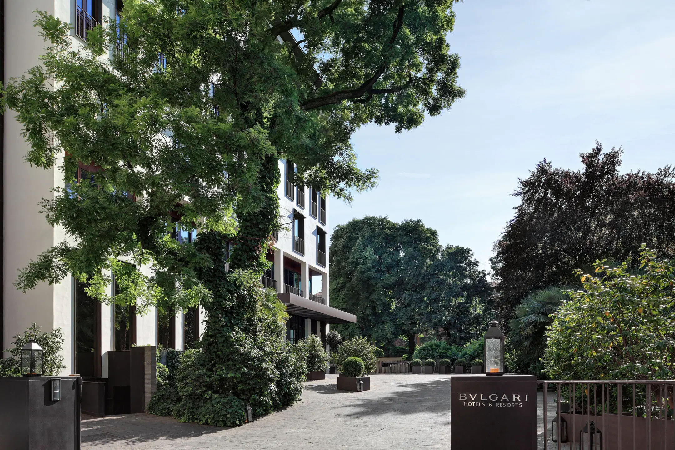 Luxury hotel entrance surrounded by lush trees, featuring a prominent Bulgari Hotels & Resorts sign.