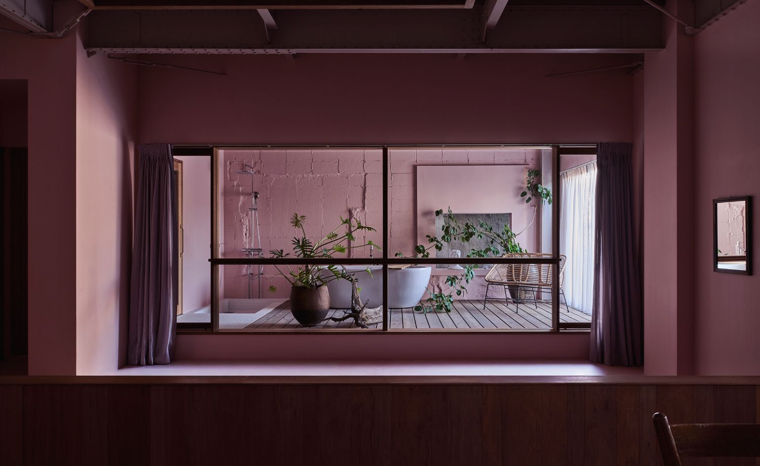 Exterior view of Tayura hotel in Nara, showcasing its distinctive pink facade amidst traditional Japanese architecture.