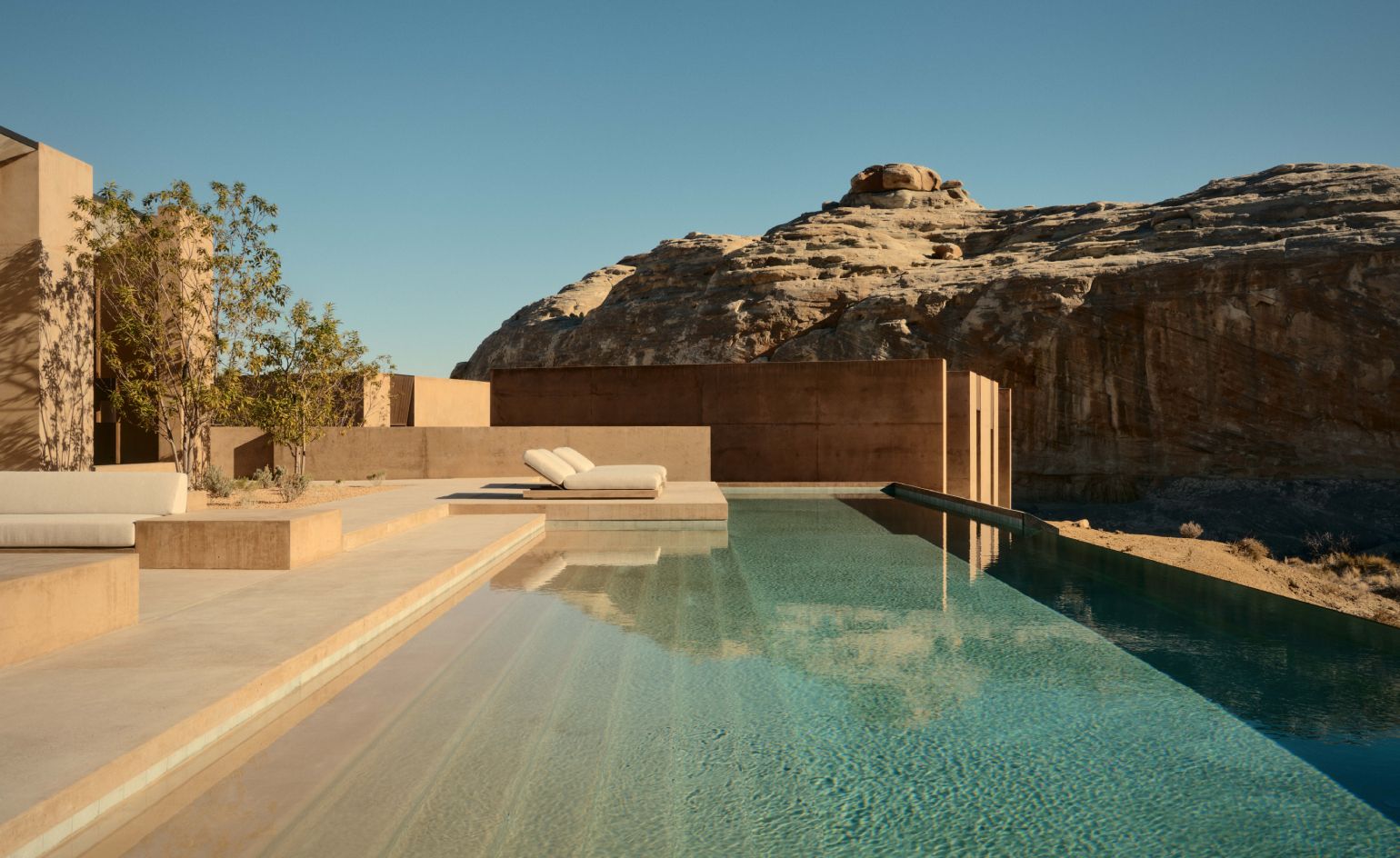 An aerial view of a modern luxury villa with a large swimming pool, integrated into a red rock desert landscape, likely at Amangiri.