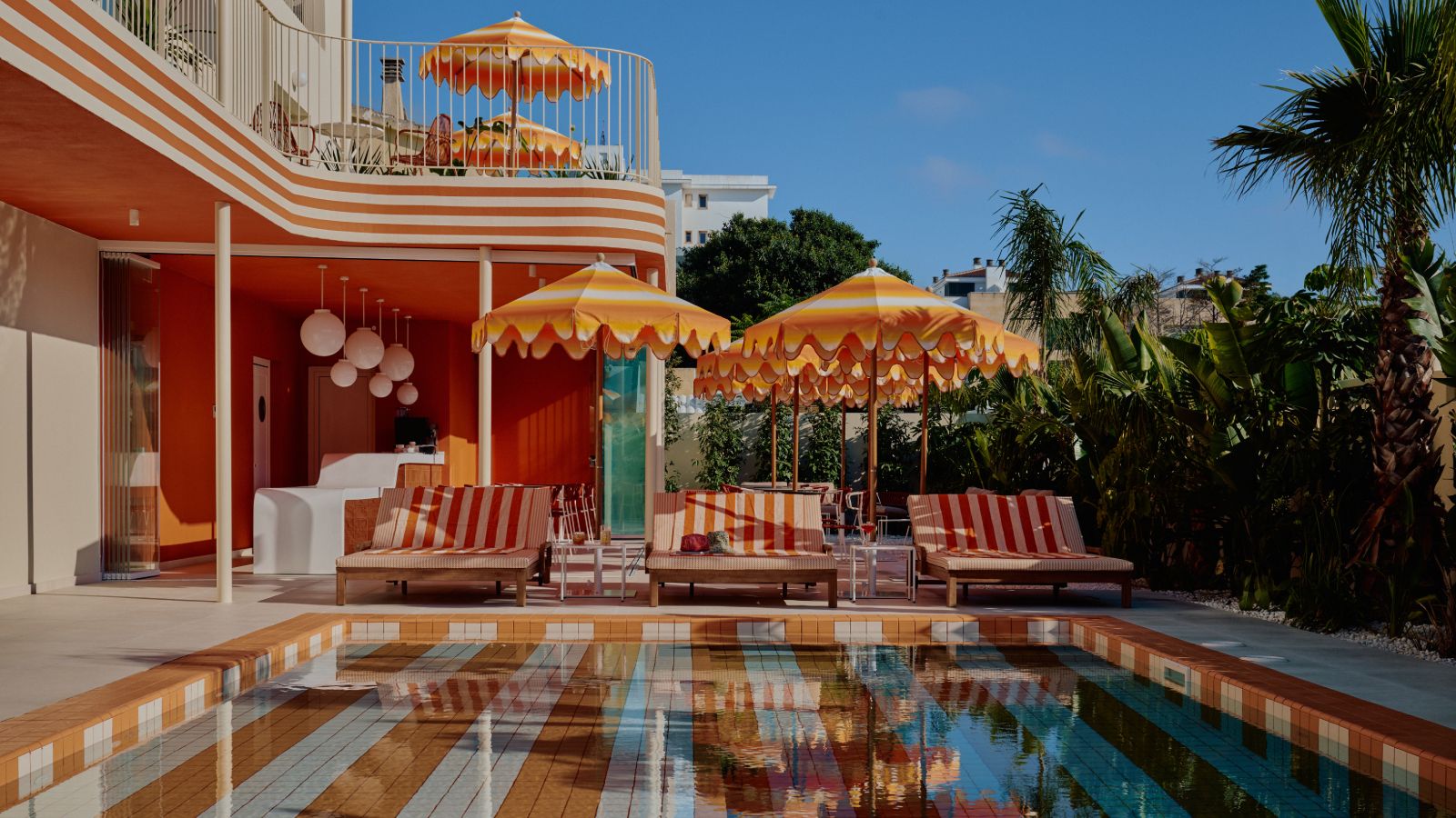 Exterior view of Riviera Hotel Menorca, showing colorful architecture and a poolside area.