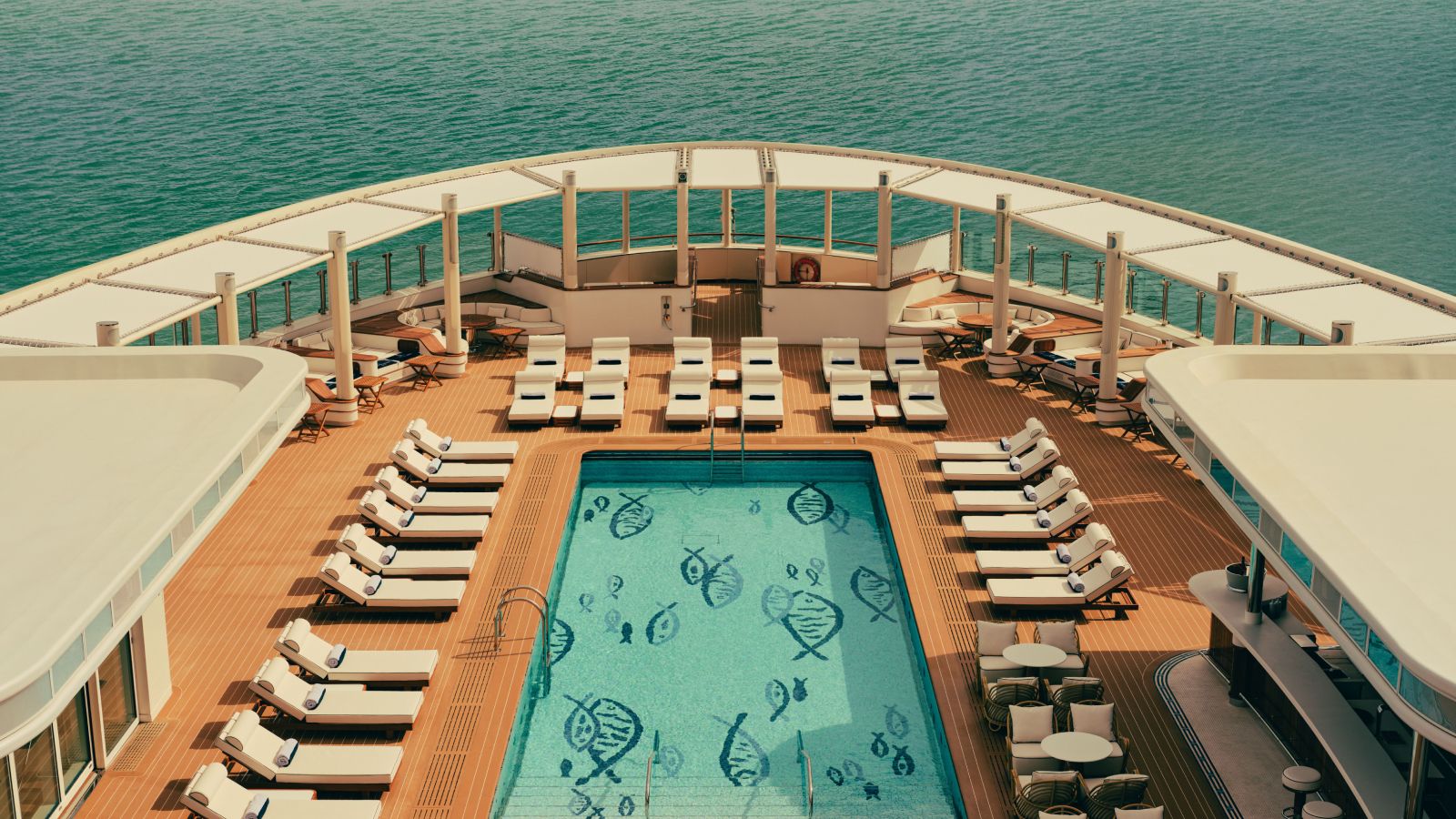 A luxury yacht, the Four Seasons I, sailing gracefully on calm turquoise waters near a scenic coastline.
