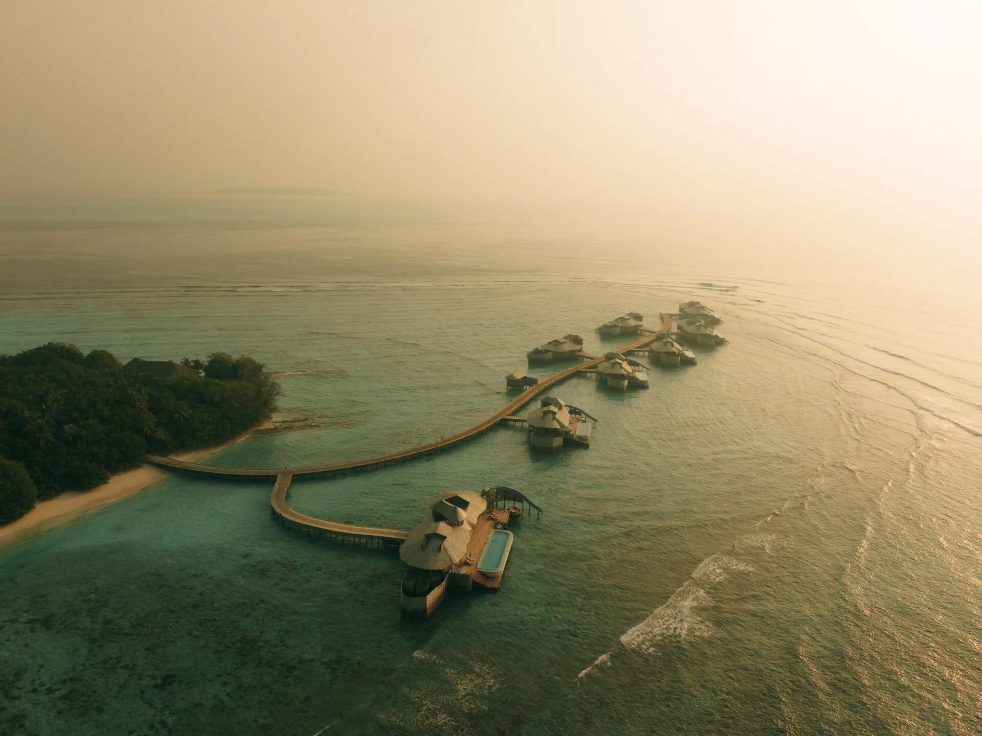 Aerial view of Soneva Fushi's overwater villas amidst clear turquoise waters