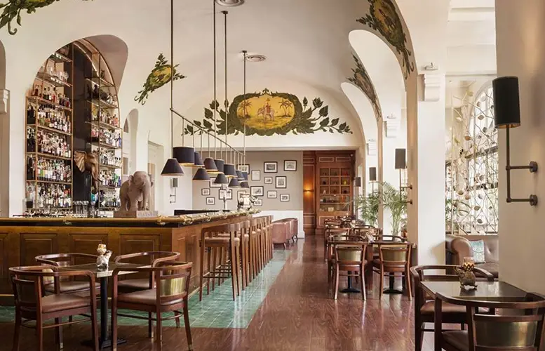 Interior of the Elephant Bar at Raffles Hotel Le Royal, featuring elegant colonial decor, plush seating, and a well-stocked bar