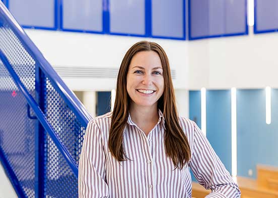 Kara dePool, a hospitality alumna, stands inside an academic building on campus.