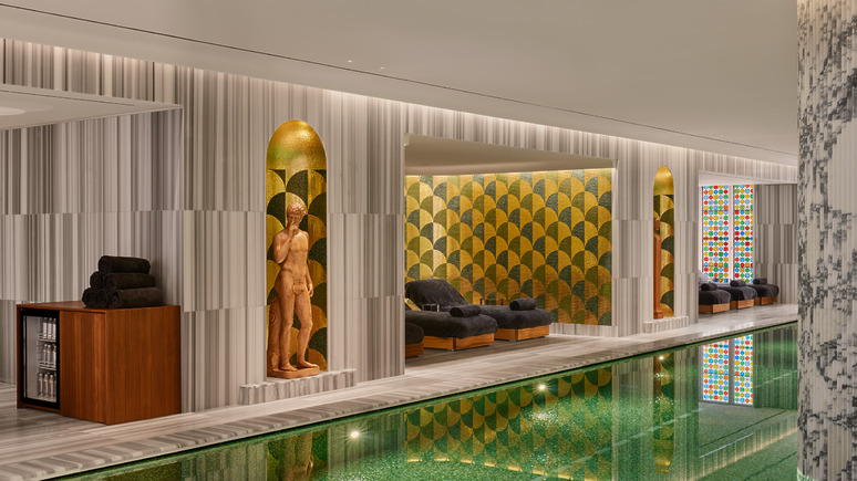 Luxurious indoor pool area at the Bulgari Hotel in Rome with stylish seating, geometric patterns, and sculptures, creating a serene and elegant atmosphere.
