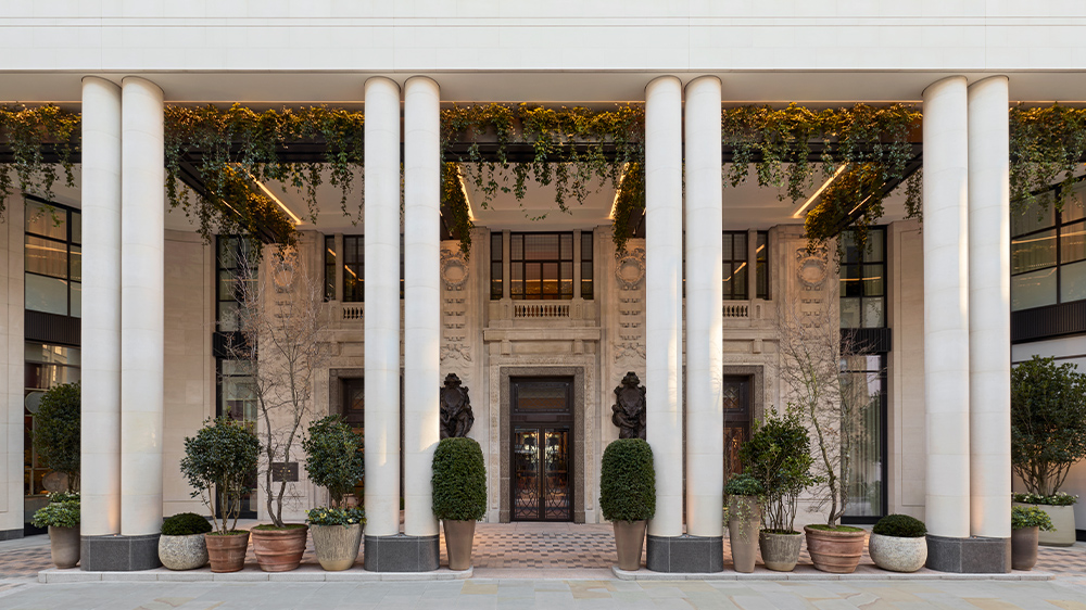 A grand hotel lobby with a restored original marble staircase and a green-and-white checkerboard floor.