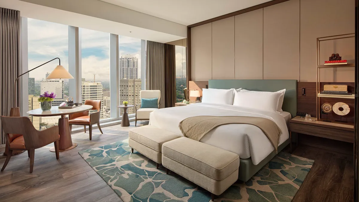 Exterior view of a modern high-rise hotel, the Mandarin Oriental Makati, Manila, with balconies and a sleek facade.