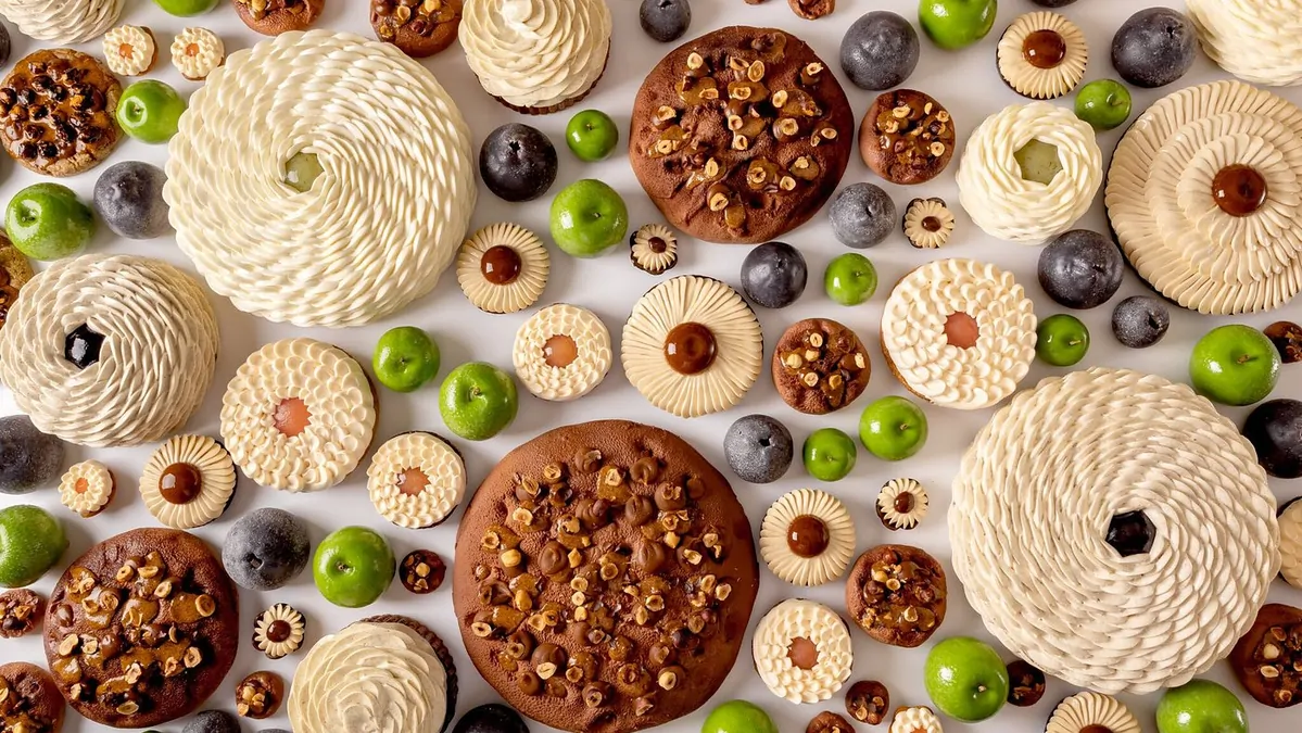 A display case filled with various pastries and baked goods at a luxury hotel bakery, with blurred figures of people in the background.