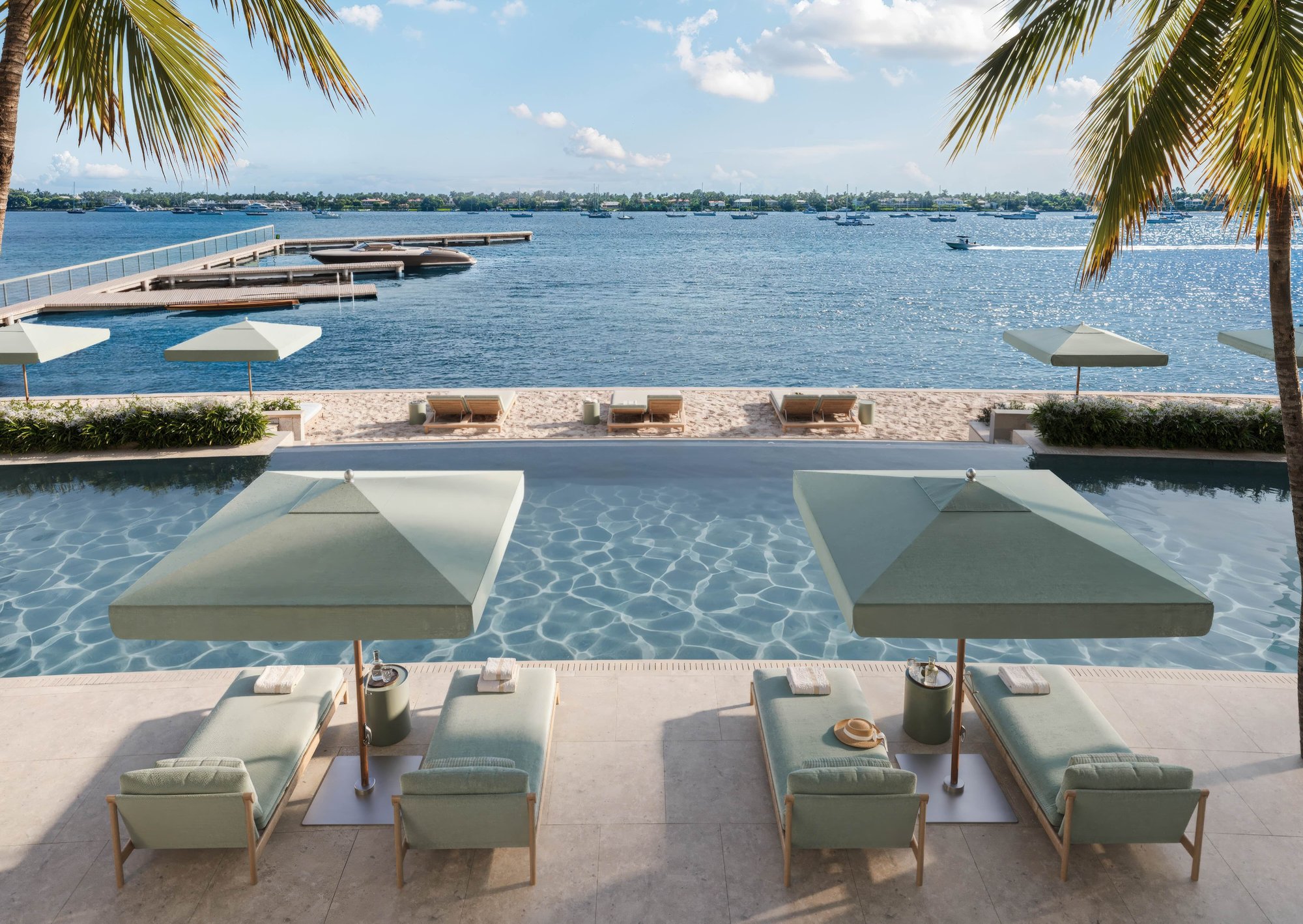Renderings of a modern, tall residential tower with expansive windows and balconies, overlooking a body of water with boats.