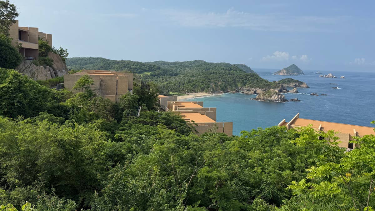A modern, open-air luxury resort structure nestled within a lush, dense jungle landscape overlooking the ocean.