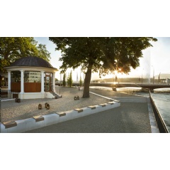 Aerial view of Lake Geneva with the Jet d'Eau fountain and Île Rousseau in the foreground, showing a small, elegant lakeside pop-up restaurant under parasols.