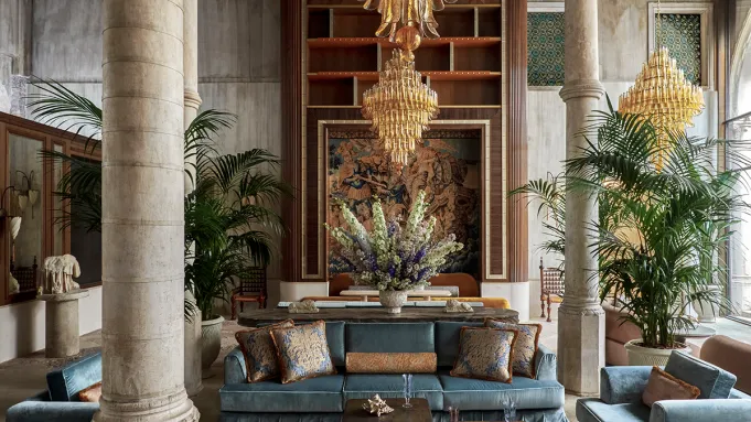 Lobby of Orient Express Venezia with sculpted wooden panels, velvet furniture, and Murano chandeliers.
