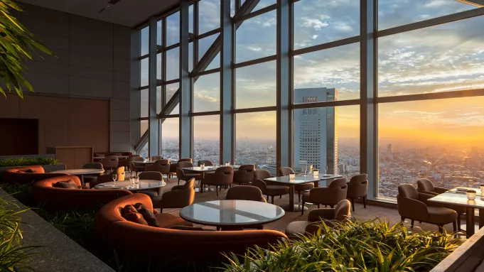 Sunrise through the windows of The Peak Lounge and Bar at Park Hyatt Tokyo, showcasing city views