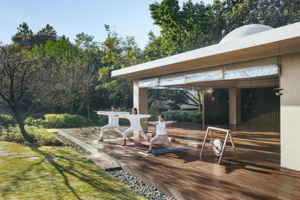 Exterior view of Six Senses Vana, showcasing lush greenery and architectural details amidst a forested backdrop.