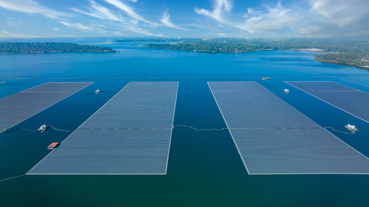 Aerial view of a luxury resort in the Maldives with a large array of floating solar panels on the turquoise water next to it.