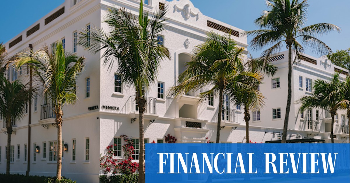 Exterior view of The Vineta Palm Beach, a luxurious pink-hued hotel building with classic architecture and lush landscaping.