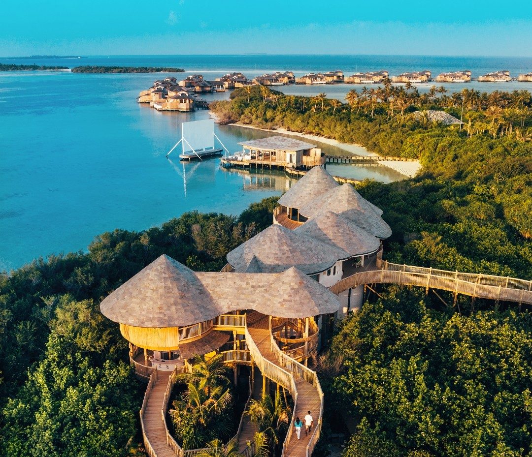 Aerial view of a sustainable luxury resort nestled within a lush natural landscape, showcasing integrated design and minimal environmental disturbance.