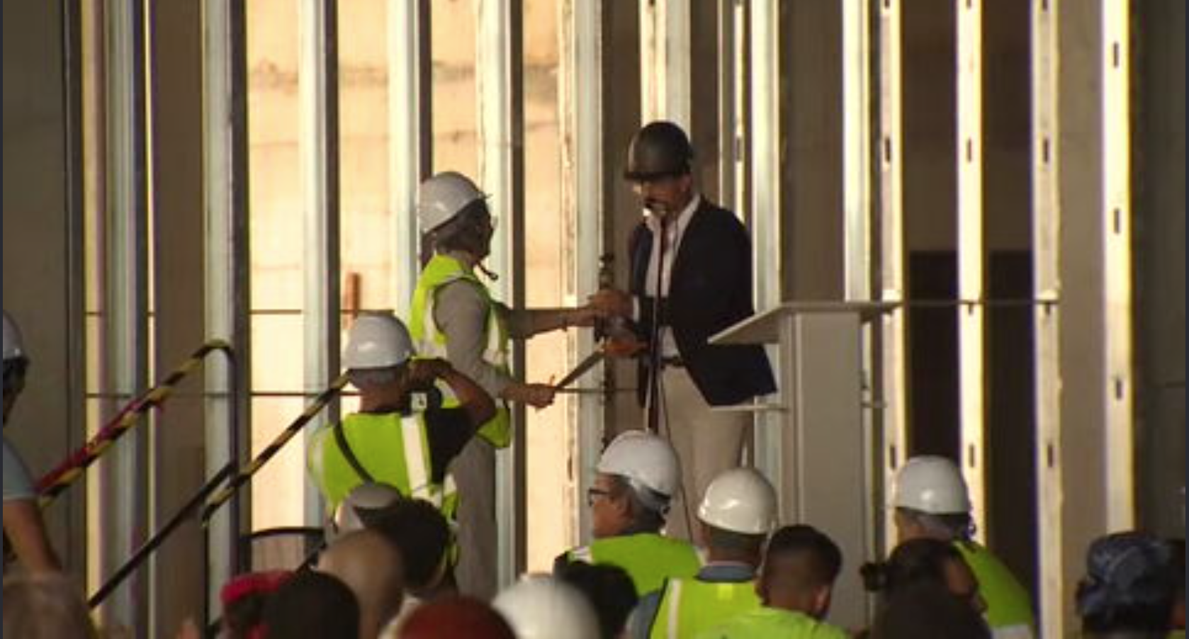 Miami Beach city and county leaders gathered at a construction site, likely for the Grand Hyatt Hotel, with a large building frame in the background.