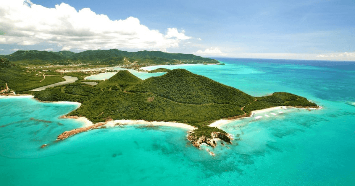 Aerial view of a pristine caribbean peninsula with lush green hills, white-sand beaches, and turquoise waters, suggesting a luxury resort development.