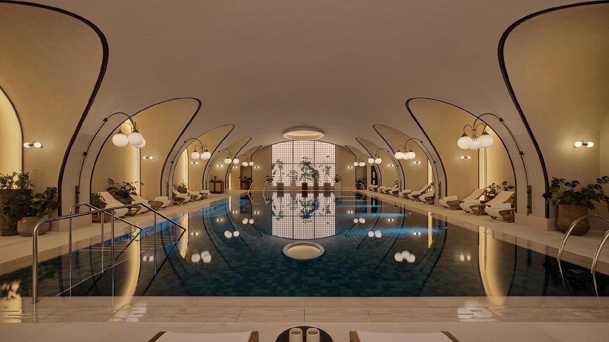 An arched hallway leading to a serene indoor pool with soft lighting