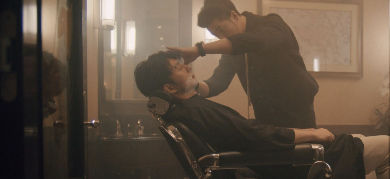 A well-appointed, classic barbershop interior within a luxury hotel, featuring traditional barber chairs and warm wood paneling.