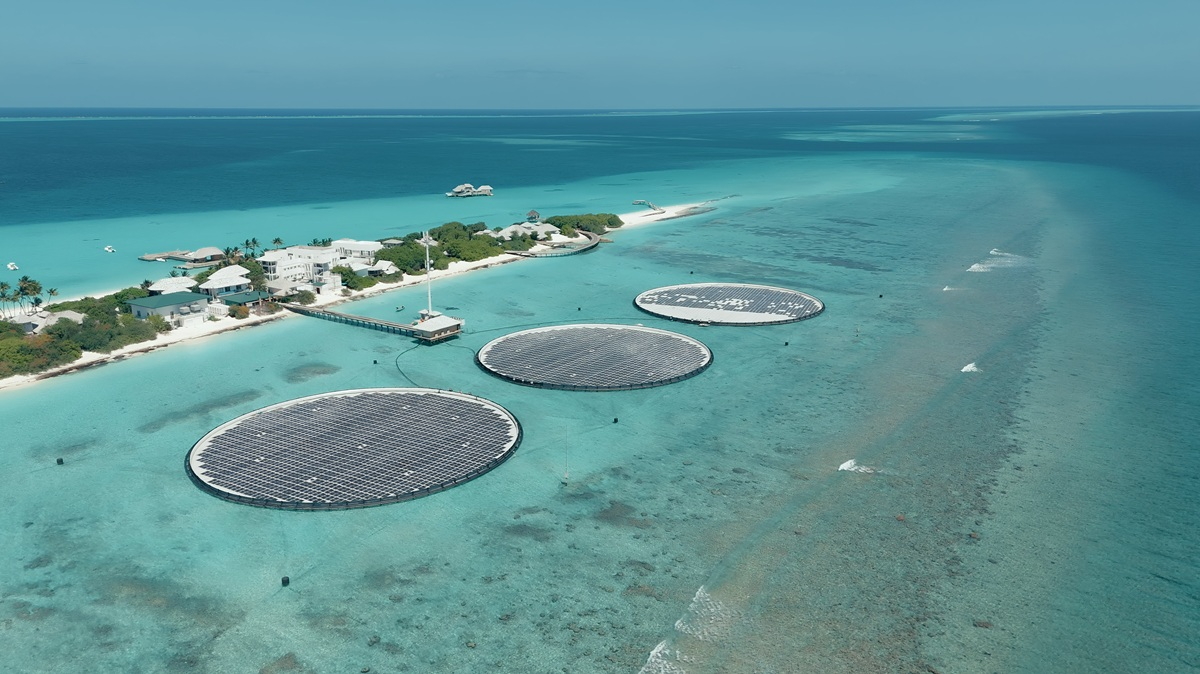 Aerial view of a luxury resort in the Maldives with floating solar panels on the water and villas on stilts