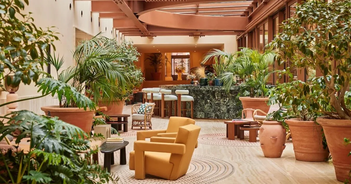 The opulent lobby at Six Senses Rome, featuring a grand marble staircase and abundant greenery.