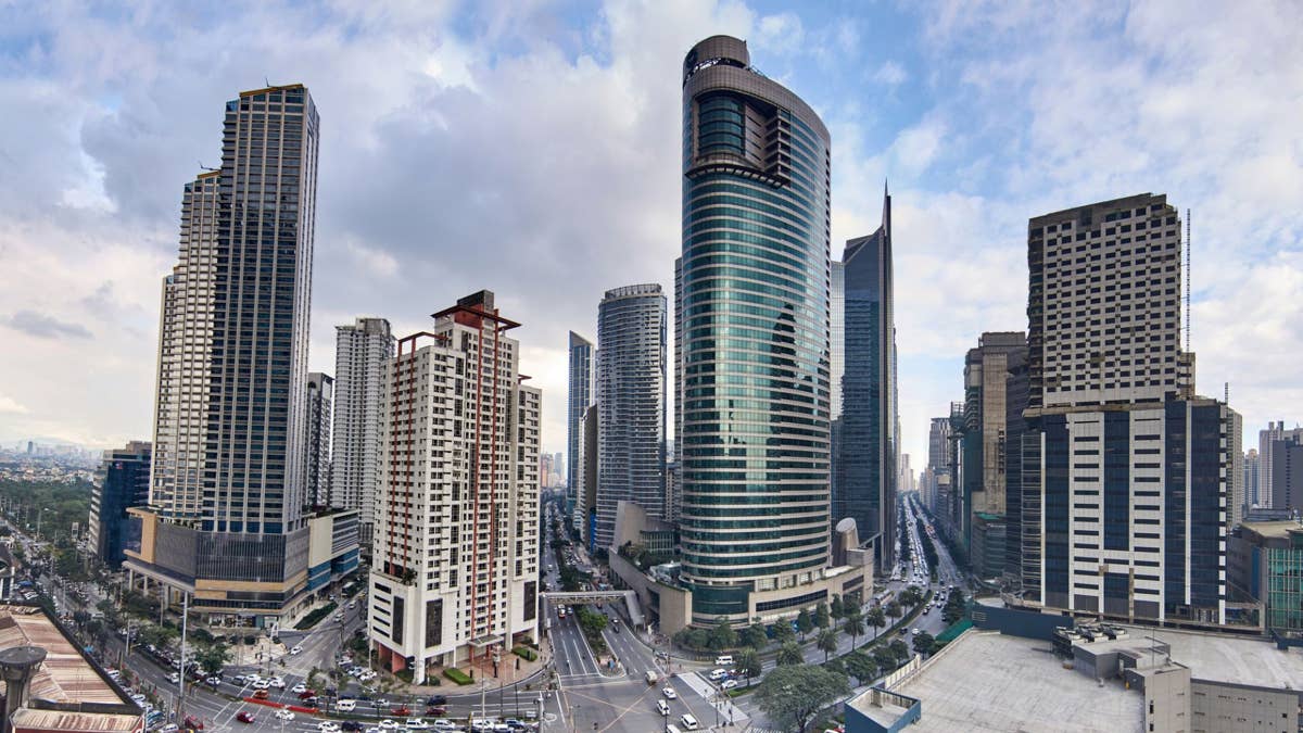 The modern skyline of Manila at dusk, with glowing skyscrapers and city lights
