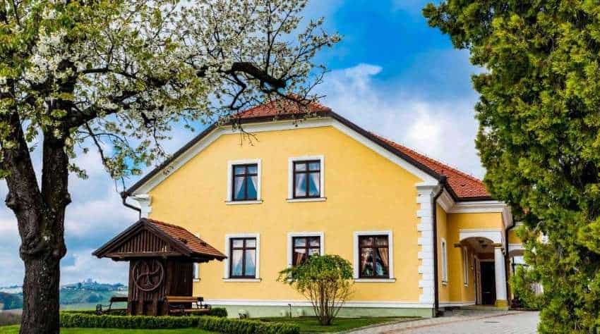 Charming yellow hotel in Međimurje, Croatia, surrounded by lush greenery and vineyards.