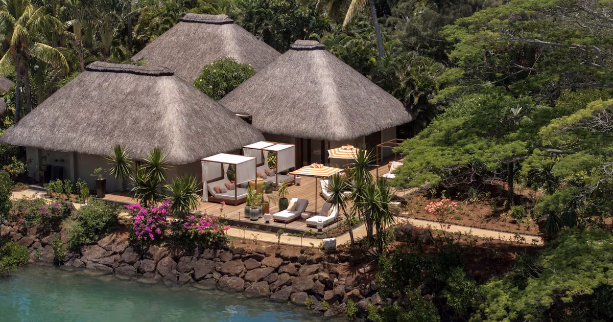 Aerial view of luxury villas integrated into lush green landscape along a coastline with the ocean nearby